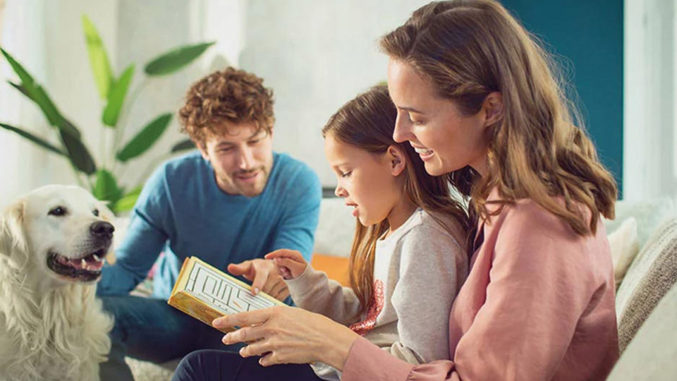 Family reading a book together with their dog
